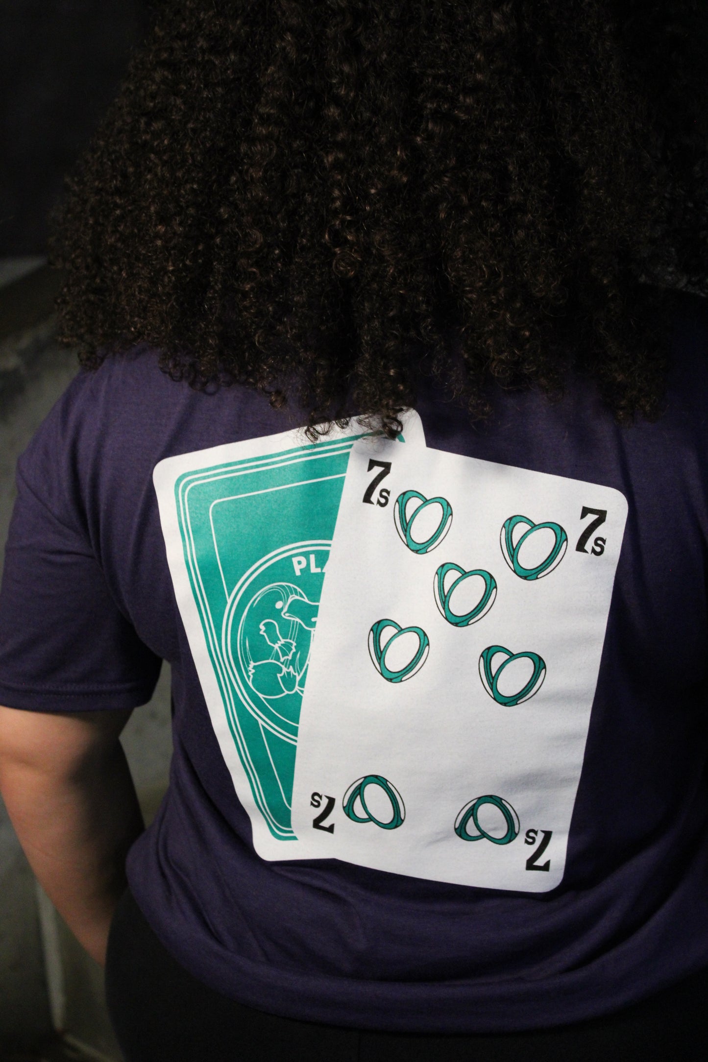 Person wearing a dark shirt with playing cards on the back of the shirt