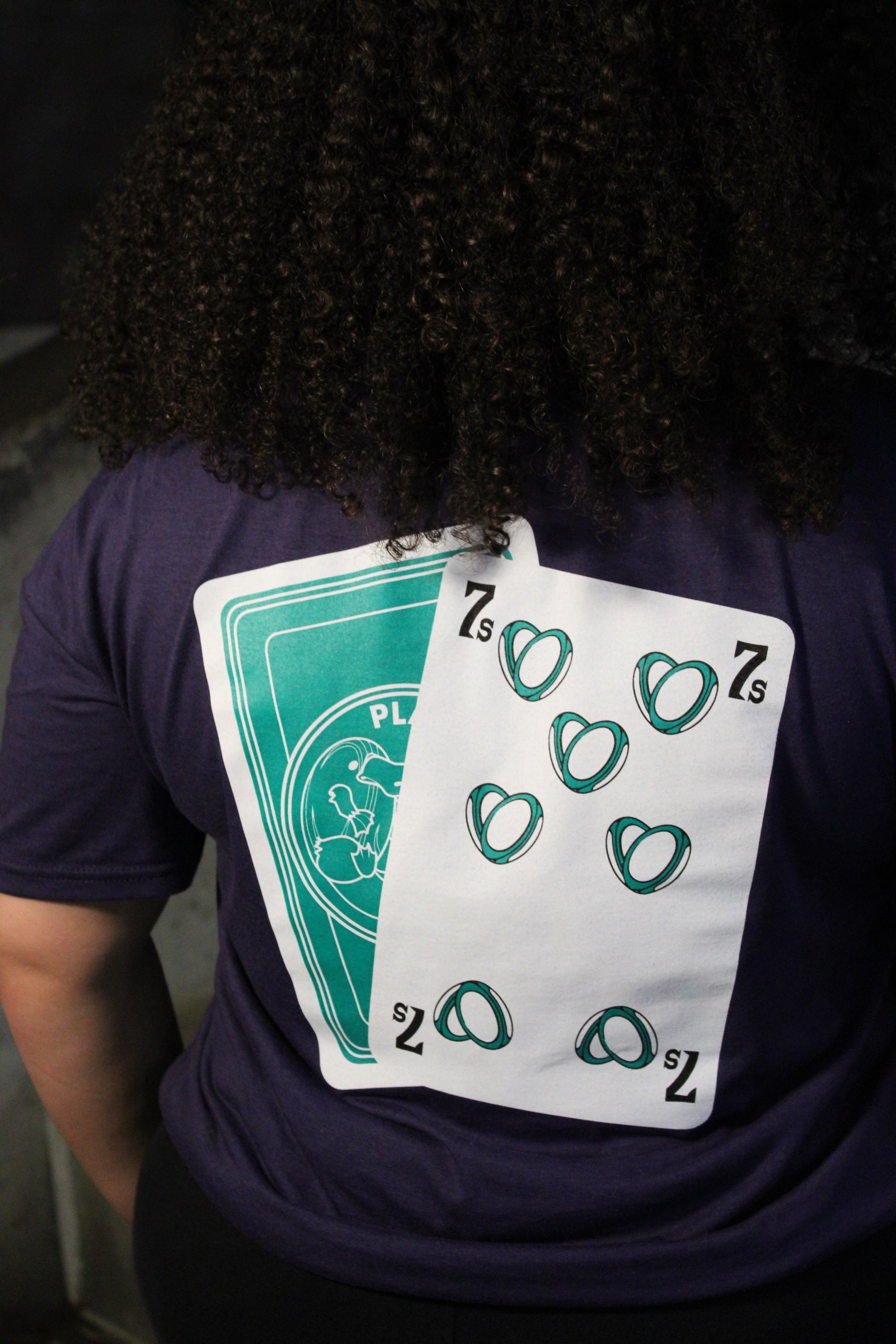 Person wearing a dark shirt with playing cards on the back of the shirt